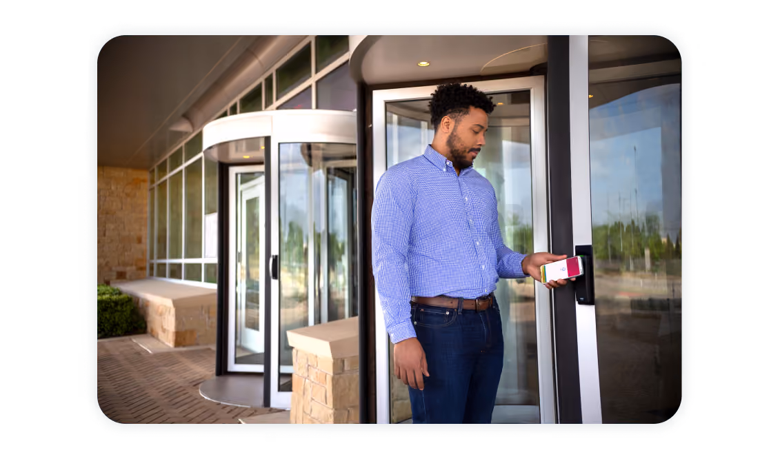 Man unlocking a modern office door using iPhone with Apple Wallet badge, demonstrating seamless mobile access via Sharry platform
