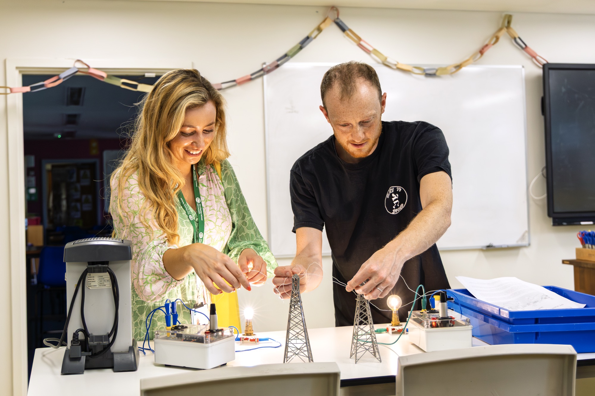 Two teachers testing a hands-on electricity activity with model pylons and bulbs at a training session