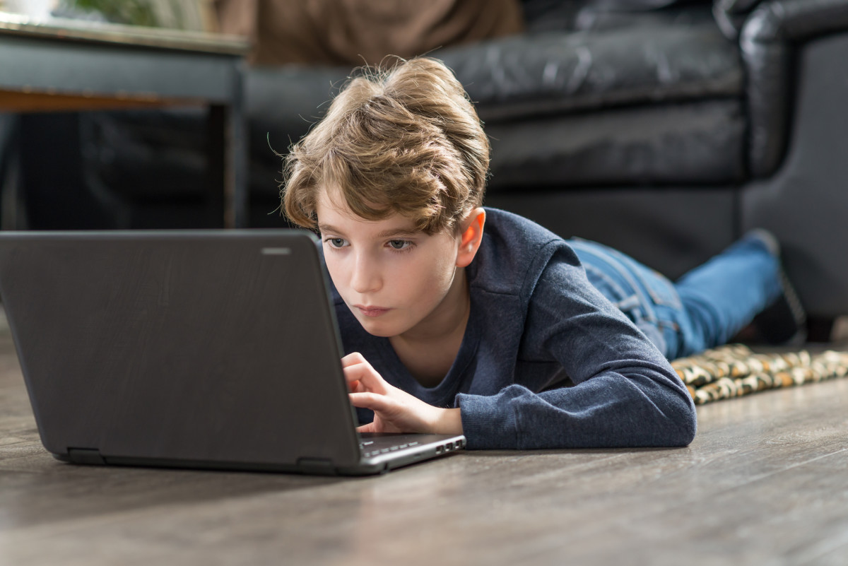 Photo of a student on the floor and working on a laptop