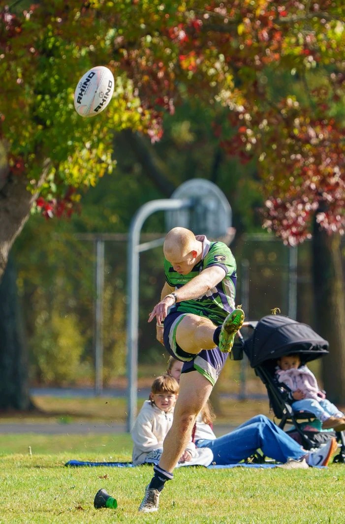 A Seattle kicker strikes the ball off the tee as families watch from the sideline during Seattle's 82-0 win, October 10, 2026