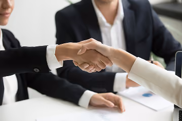 Business partners shaking hands while signing a contract
