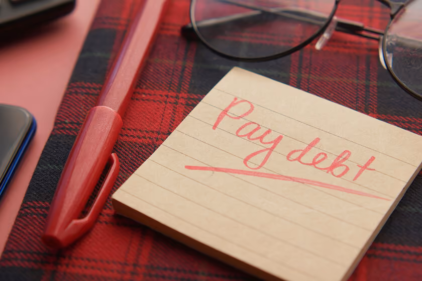 Post it note with 'pay debt' written on it