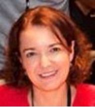 femme souriante en veste rouge portant un badge noir et un micro durant une session de data et intelligence artificielle