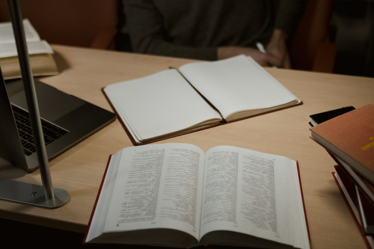 Cahier et livres ouverts sur un bureau en bois, symbole de la rentrée et de la formation