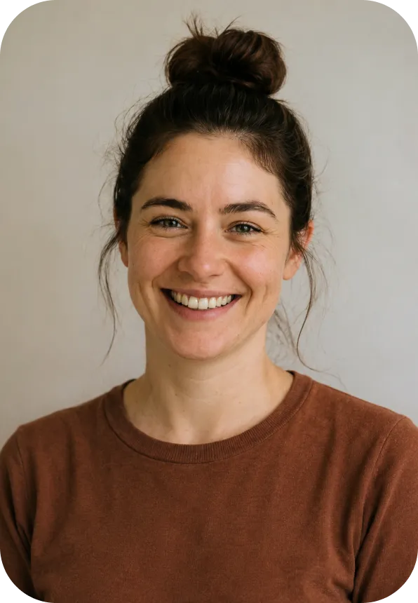 Smiling woman with brown hair in a bun wearing a brown shirt against a light background.