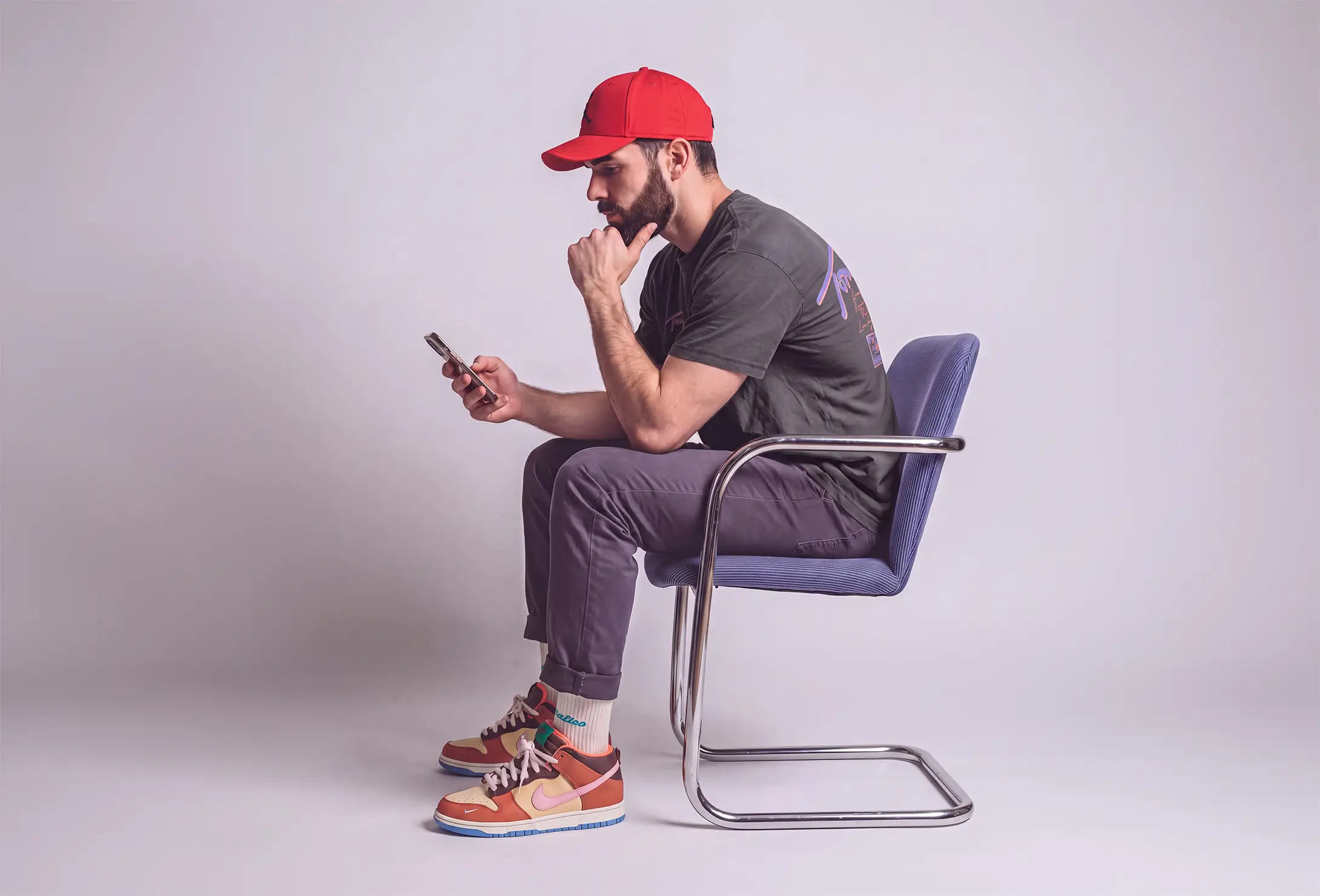 Yll Lenjani, Gründer von Y STUDIO, sitzt im Studio und blickt nachdenklich auf sein Smartphone