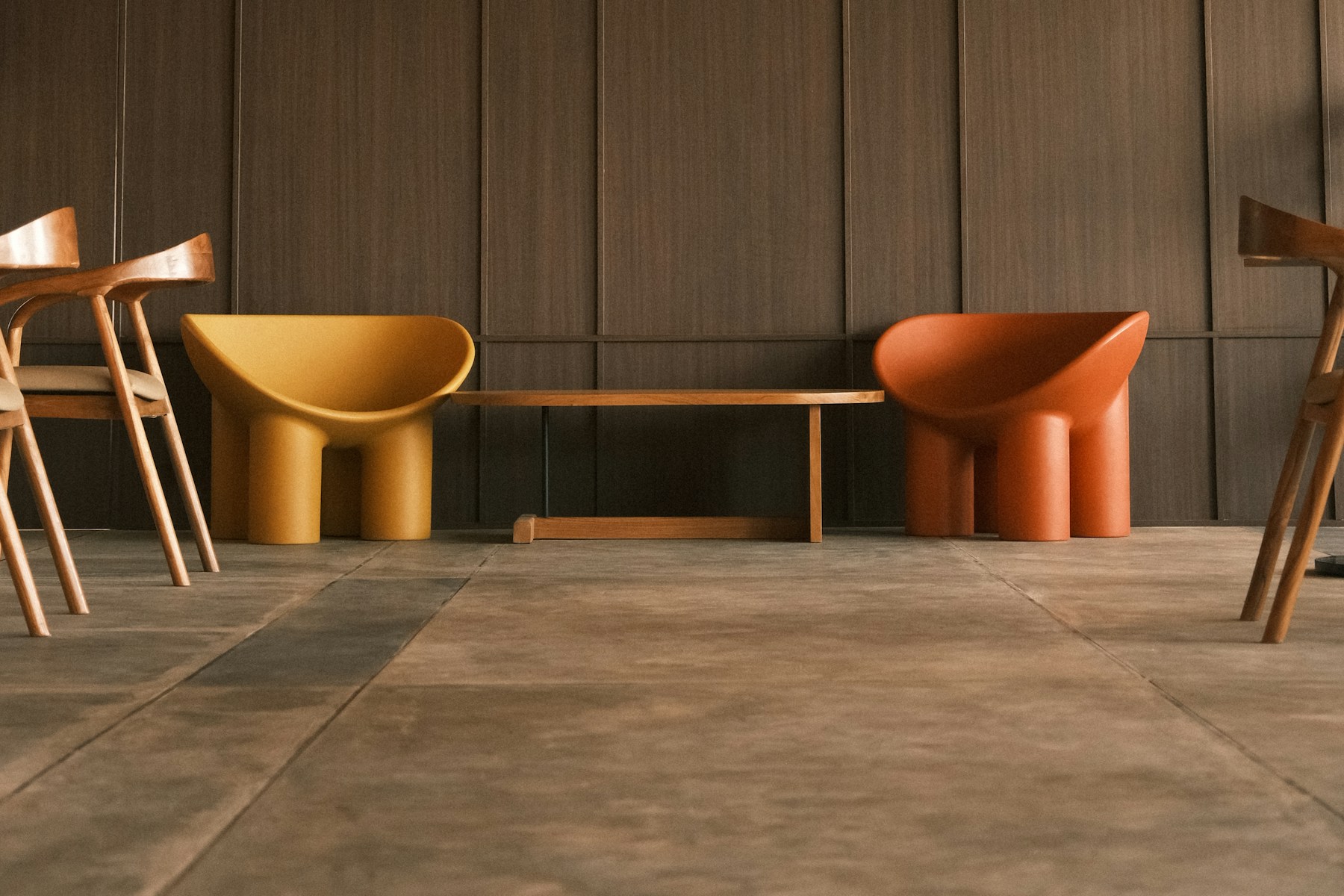 Zwei markante Designstühle in Gelb und Orange vor einer dunklen Holzwand als Symbol für klare Positionierung.