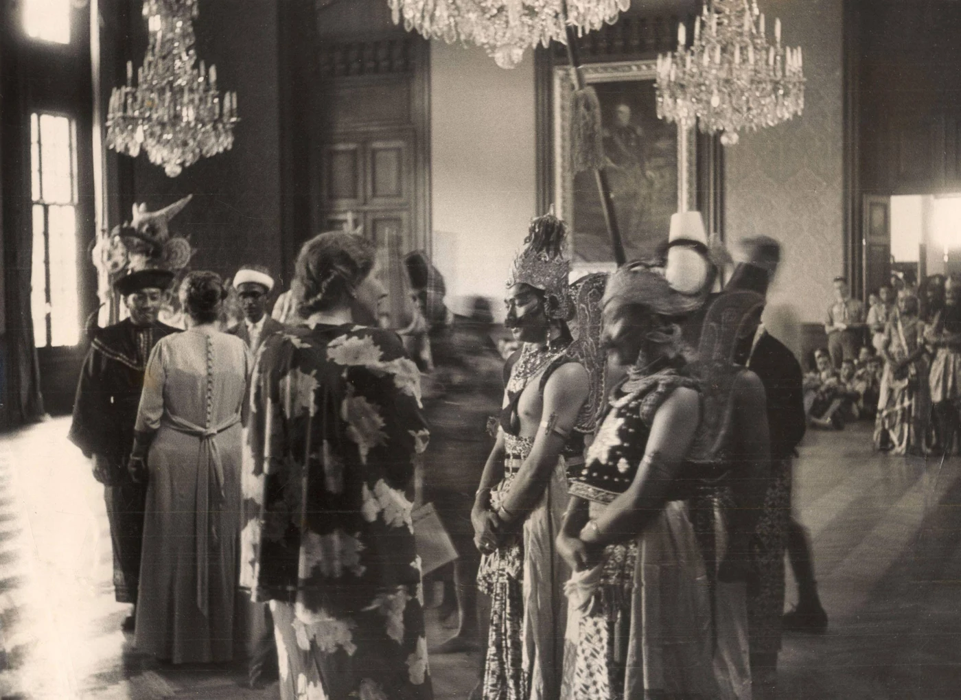 In het paleis onderhoudt prinses Juliana zich met de Wajang-dansers en ander Indische gasten. Links op de rug gezien koningin Wilhelmina. Rechts op de achtergrond kijken scouts toe (Nationaal Archief / Vereenigde Fotobureaux)