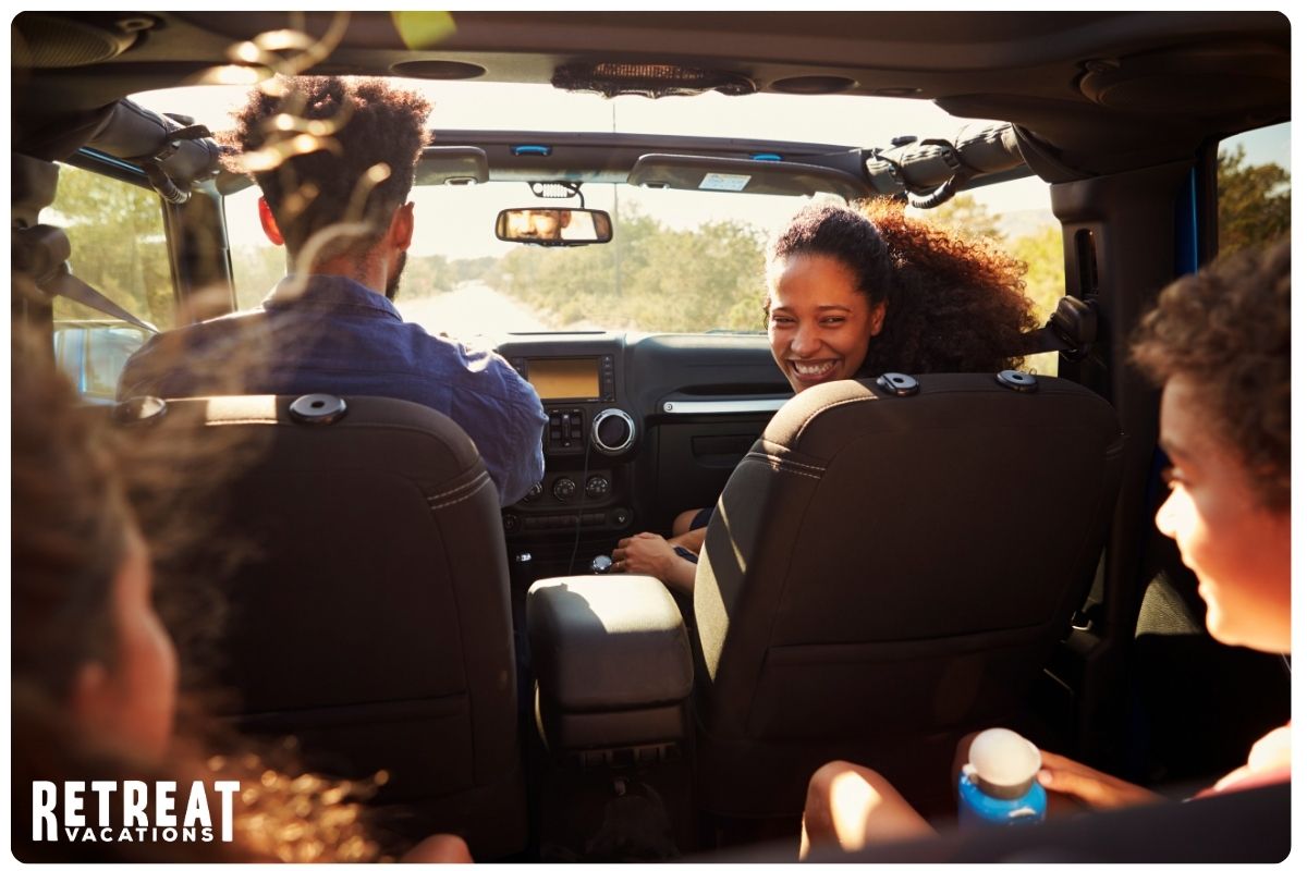 Family happily enjoying a road trip together in a car, with smiles and laughter as they travel along a scenic route.