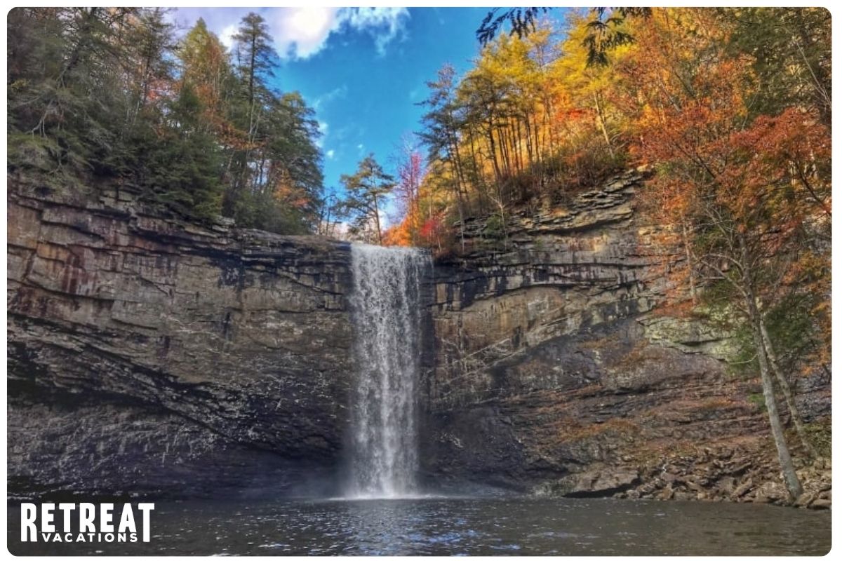 Fiery Gizzard waterfall surrounded by vibrant autumn foliage in shades of red, orange, and yellow, cascading over rocky cliffs in Tennessee