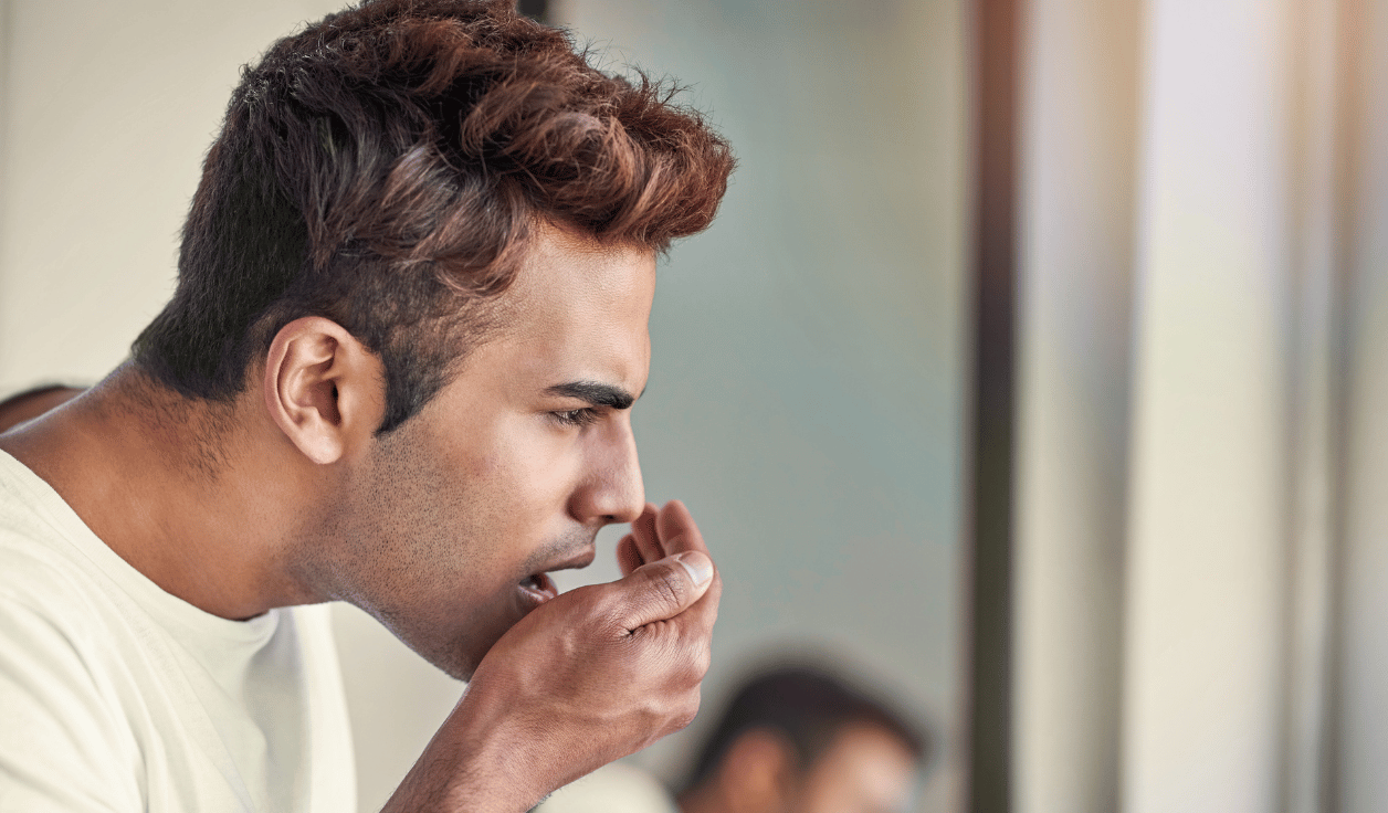 Patient covering their mouth due to bad breath while consulting a dentist.