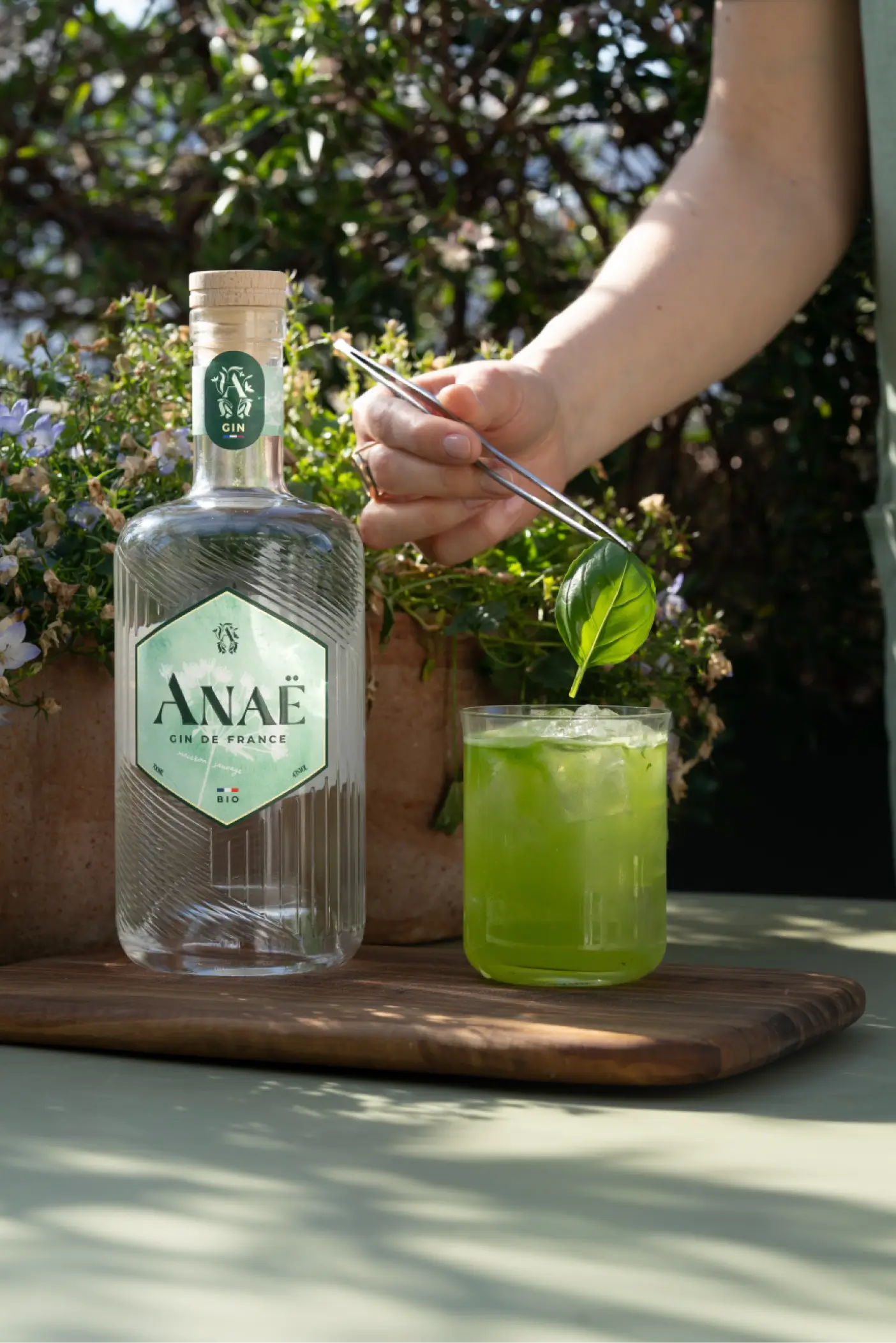 Bouteille de gin Anaë bio avec cocktail vert au basilic en préparation