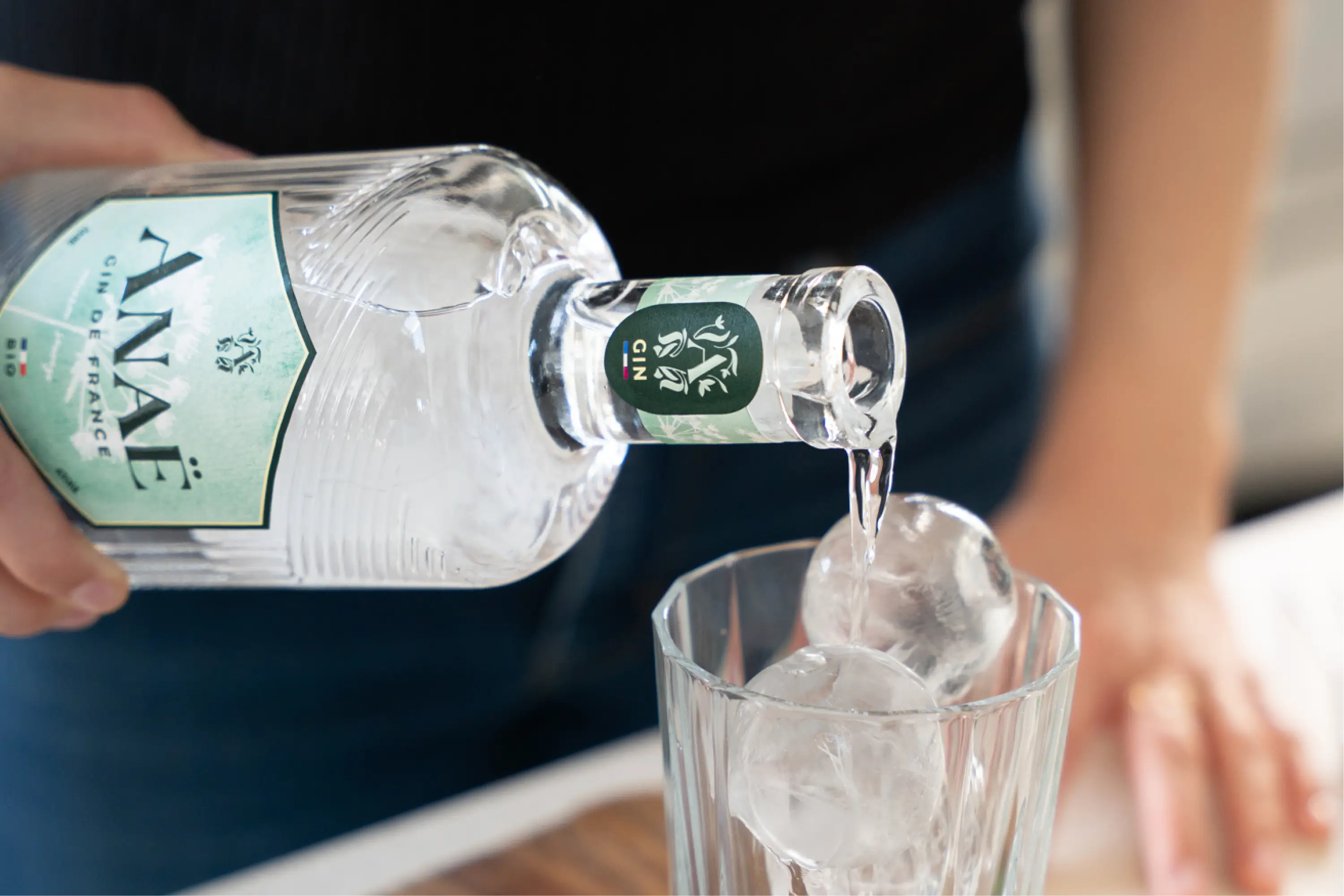 Versement du gin Anaë bio dans un verre rempli de glaçons