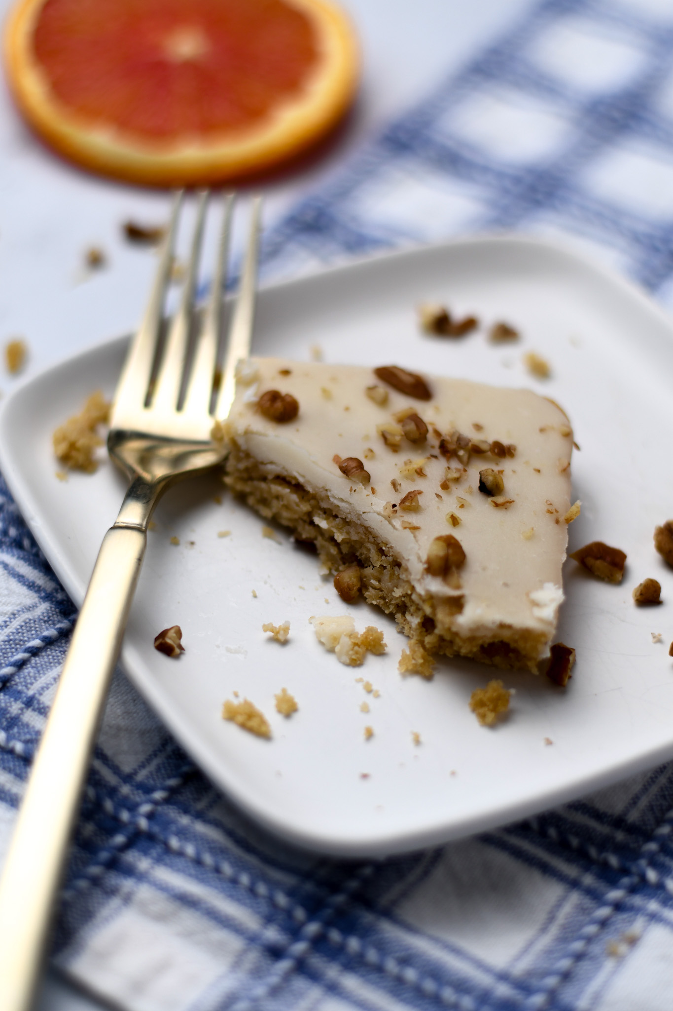 Bite missing from a slice of gluten free orange sheet cake with chopped pecans