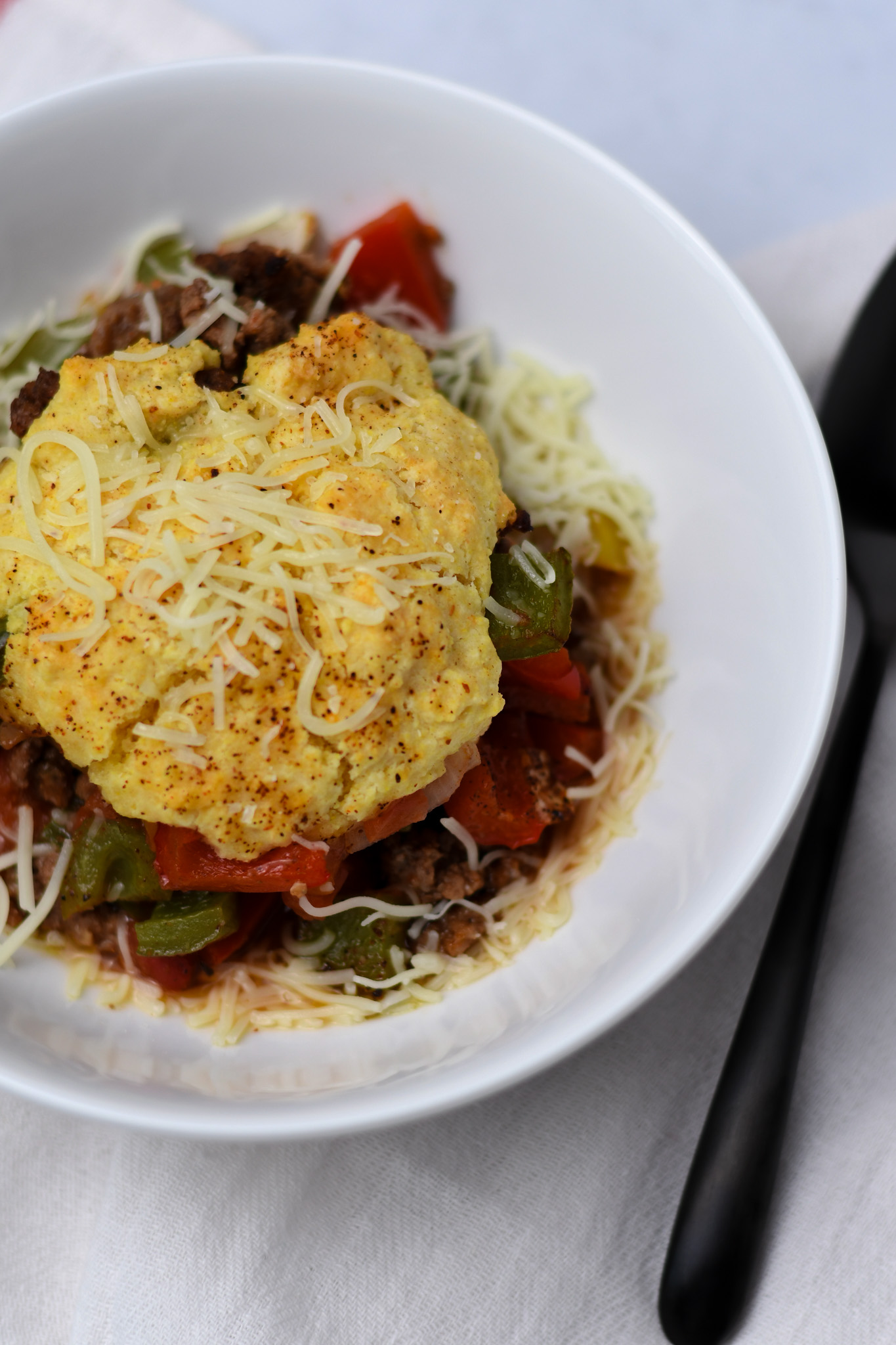 Sheet pan chili in a white bowl with a gluten free cornbread biscuit