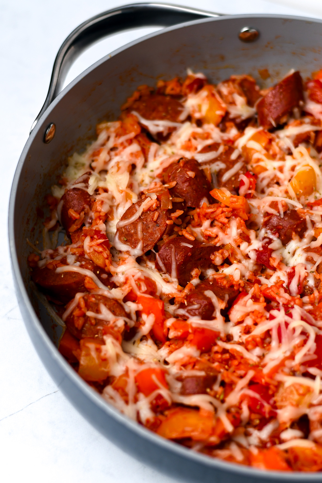 unstuffed sausage and peppers in a large skillet with rice and shredded cheese