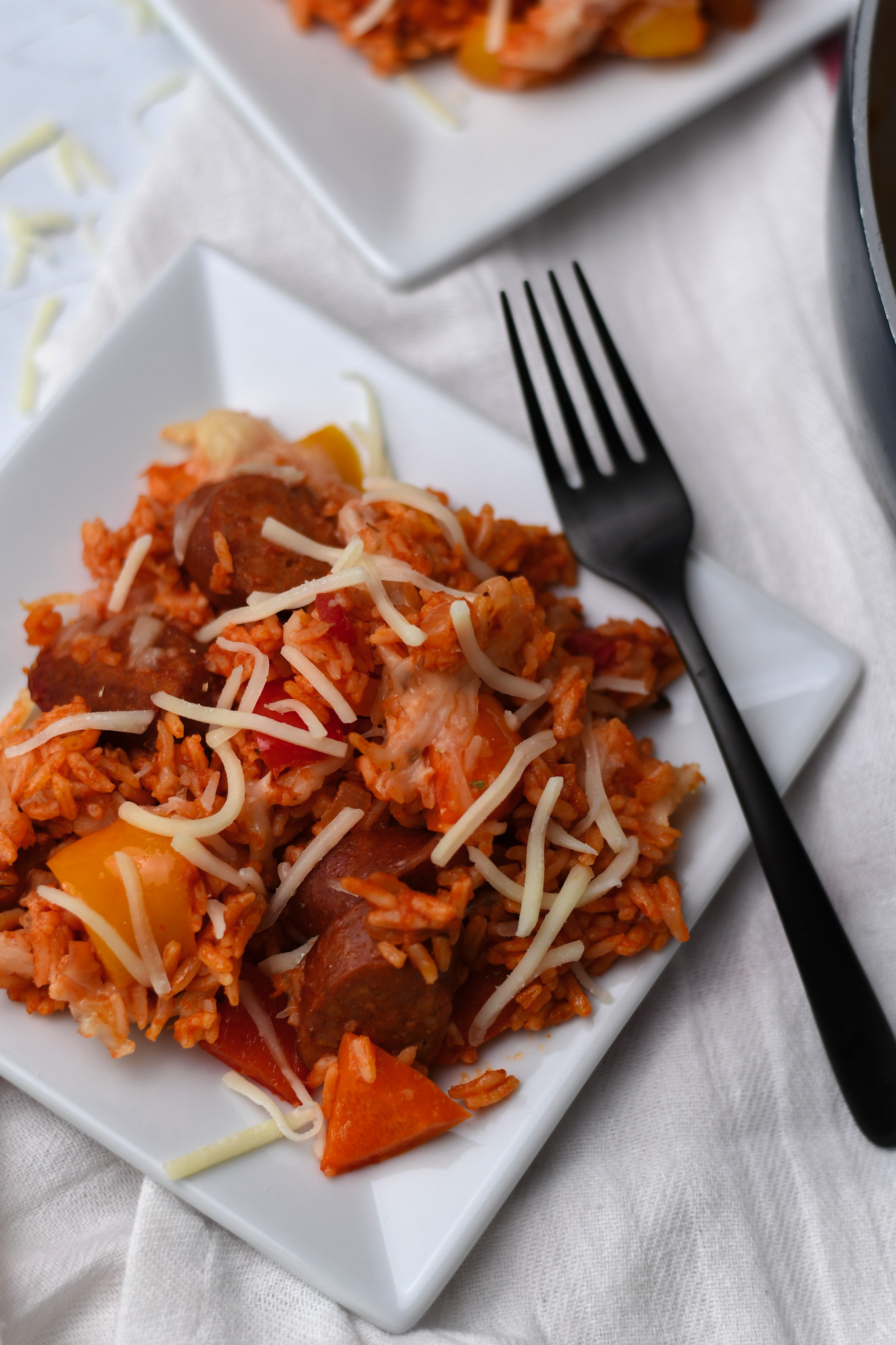 sausage and peppers with rice marinara and cheese on a white plate