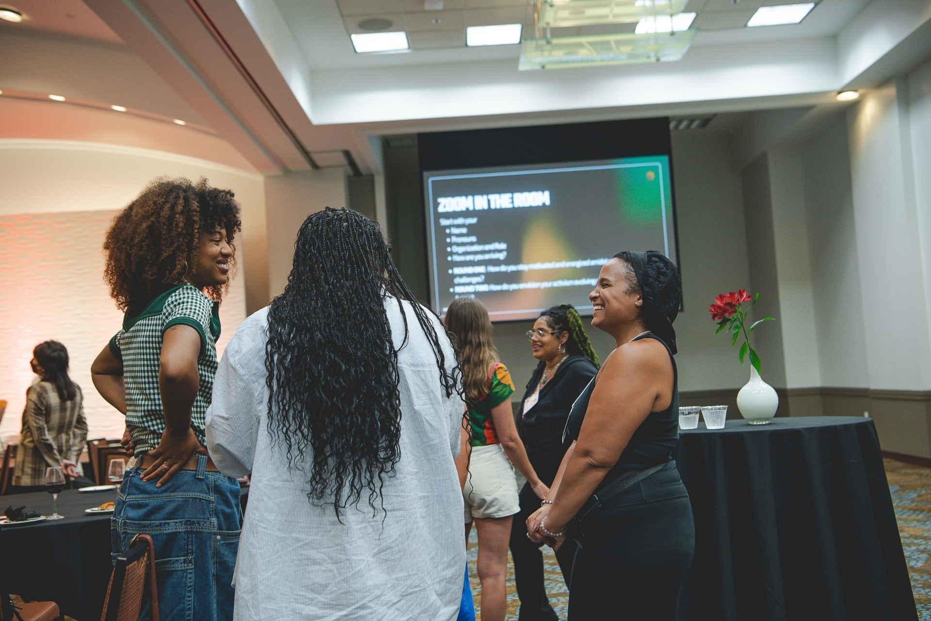 Trio of women smiling, standing in a circle and talking during the Narrative Campaign Design Sprint.