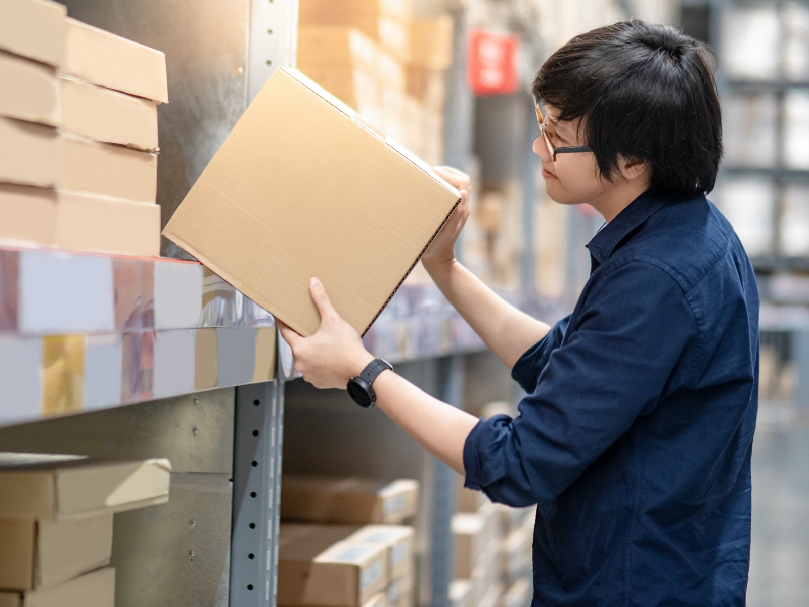 Worker inspecting a cardboard box in a warehouse storage area