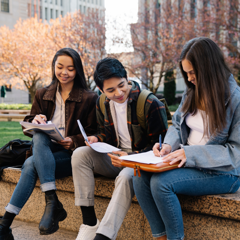 three students happily discussing and studying