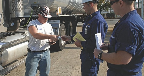 Two transportation workers are presenting their TWIC cards to someone for identification purposes
