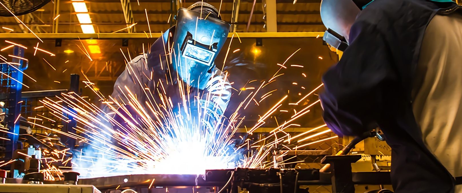 Two welders dressed in safety gears welding metals