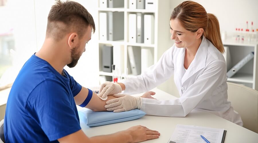 Phlebotomist wiping the antecubital region of a patient to sanitize it before drawing a blood