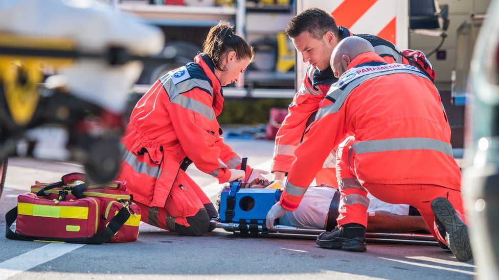 Paramedics strapping a man on a stretcher in response to an emergency