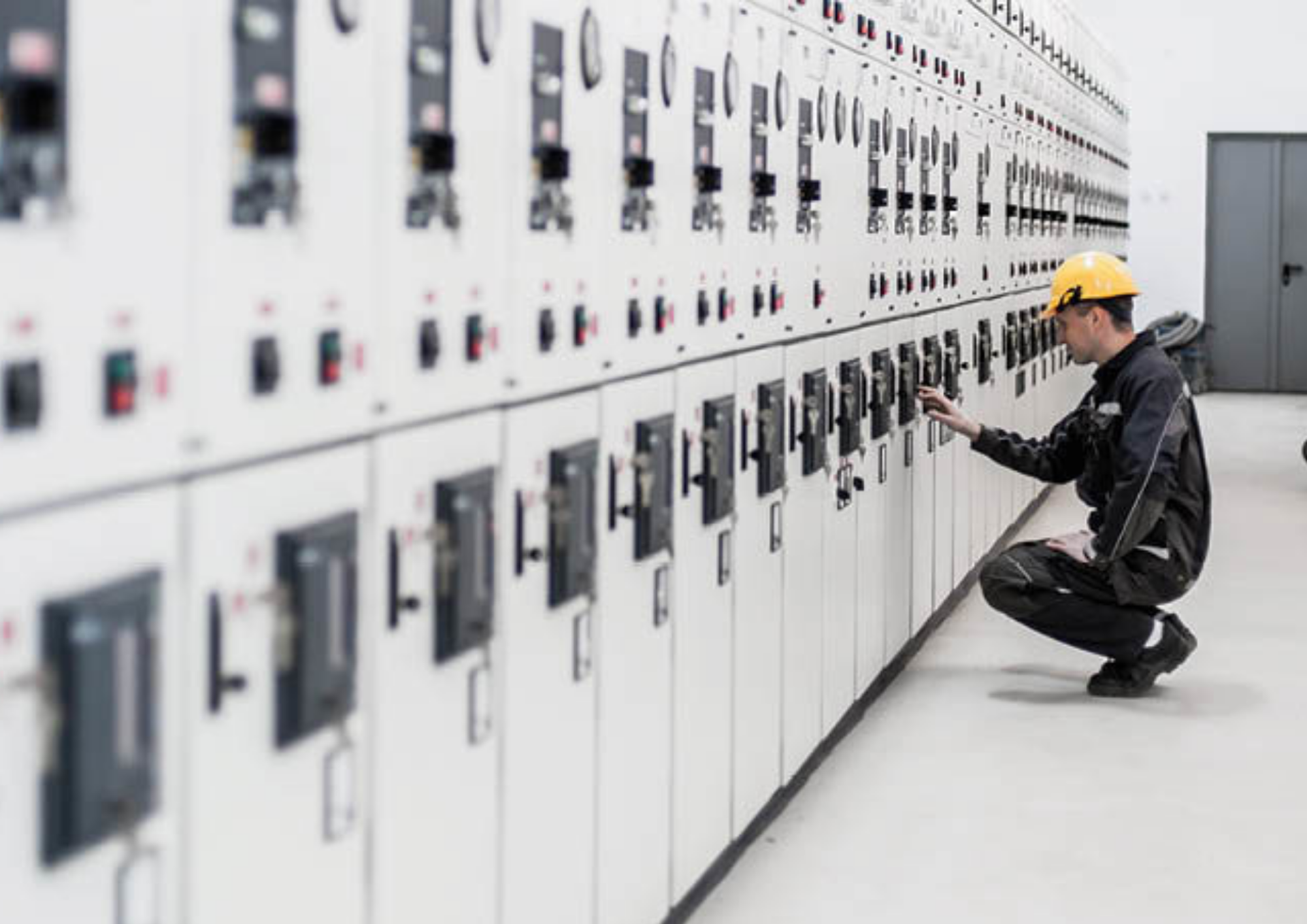 The electrician wearing hard hat is inspecting the switchgear and switchboards