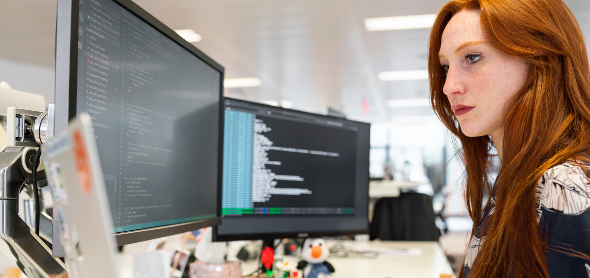 Coding associate reviewing medical records in front of three monitors