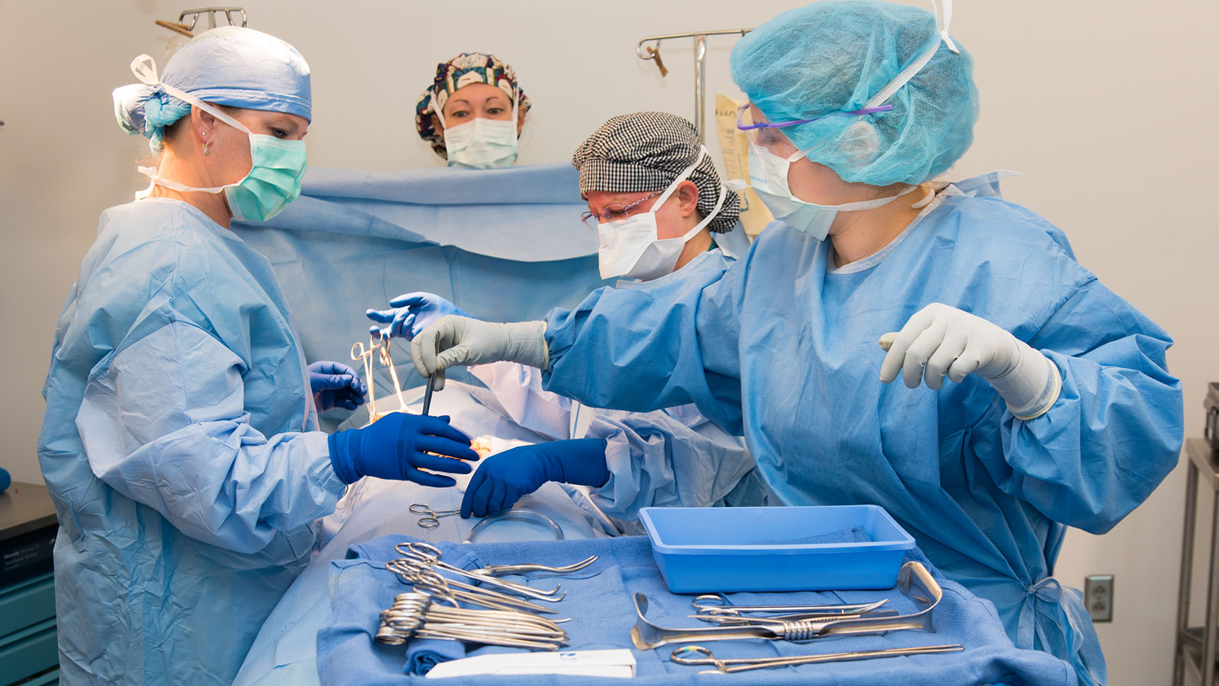 Group of Surgical Technologists wearing surgical gowns performing a surgery 