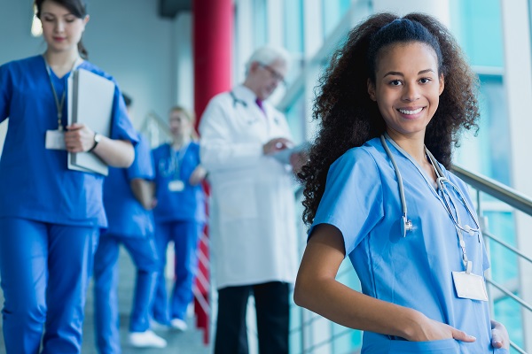 A medical assistant is smiling with four other medical assistants standing behind her
