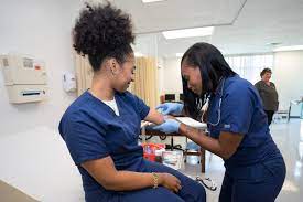 A certified medical assistant taping the antecubital region of another certified medical assistant