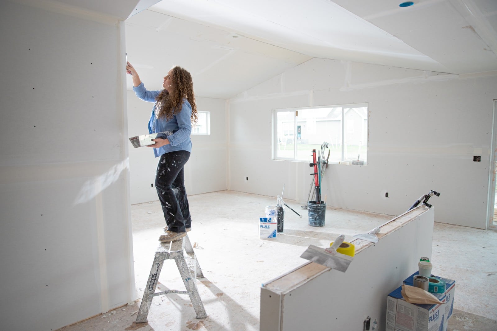 Drywall Installer is smoothing out an excess compound of plasters on the wall