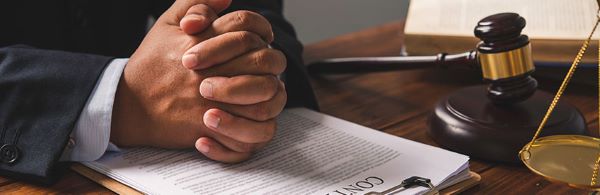 A paralegal resting his hand on the papers with a gavel beside him and a justice scale