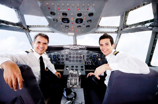 The commercial pilot and his co-pilot from the cockpit turn their heads and smile for the camera