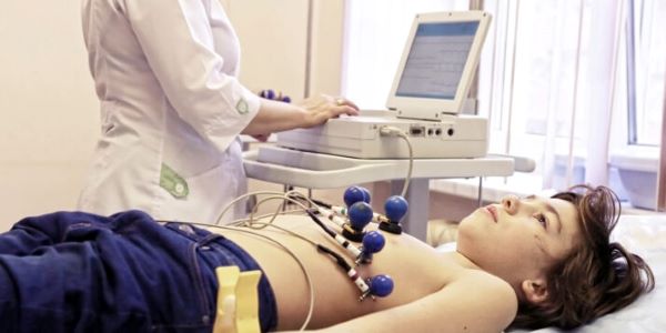 Cardiographic technician performing a diagnostic procedure to a boy