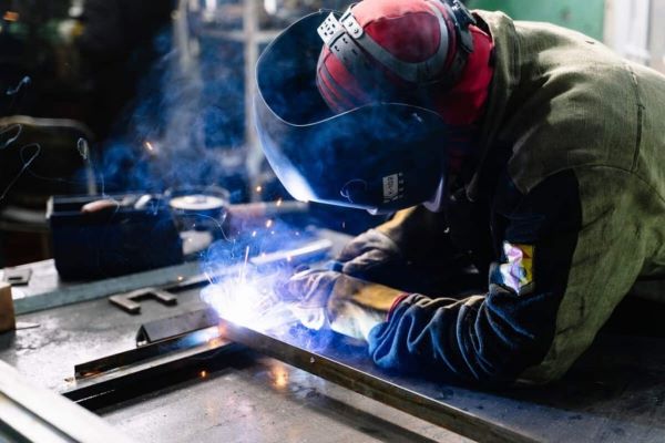 A welder wearing safety gears welding using a flux-coted electrode