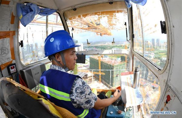 Tower crane operator works in the crane cabin at a construction site