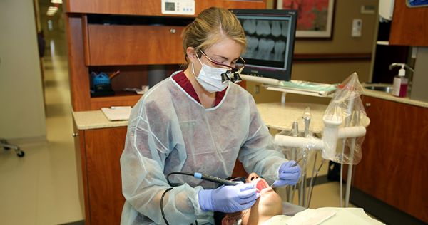 Licensed dental hygienist cleaning the mouth of her patient