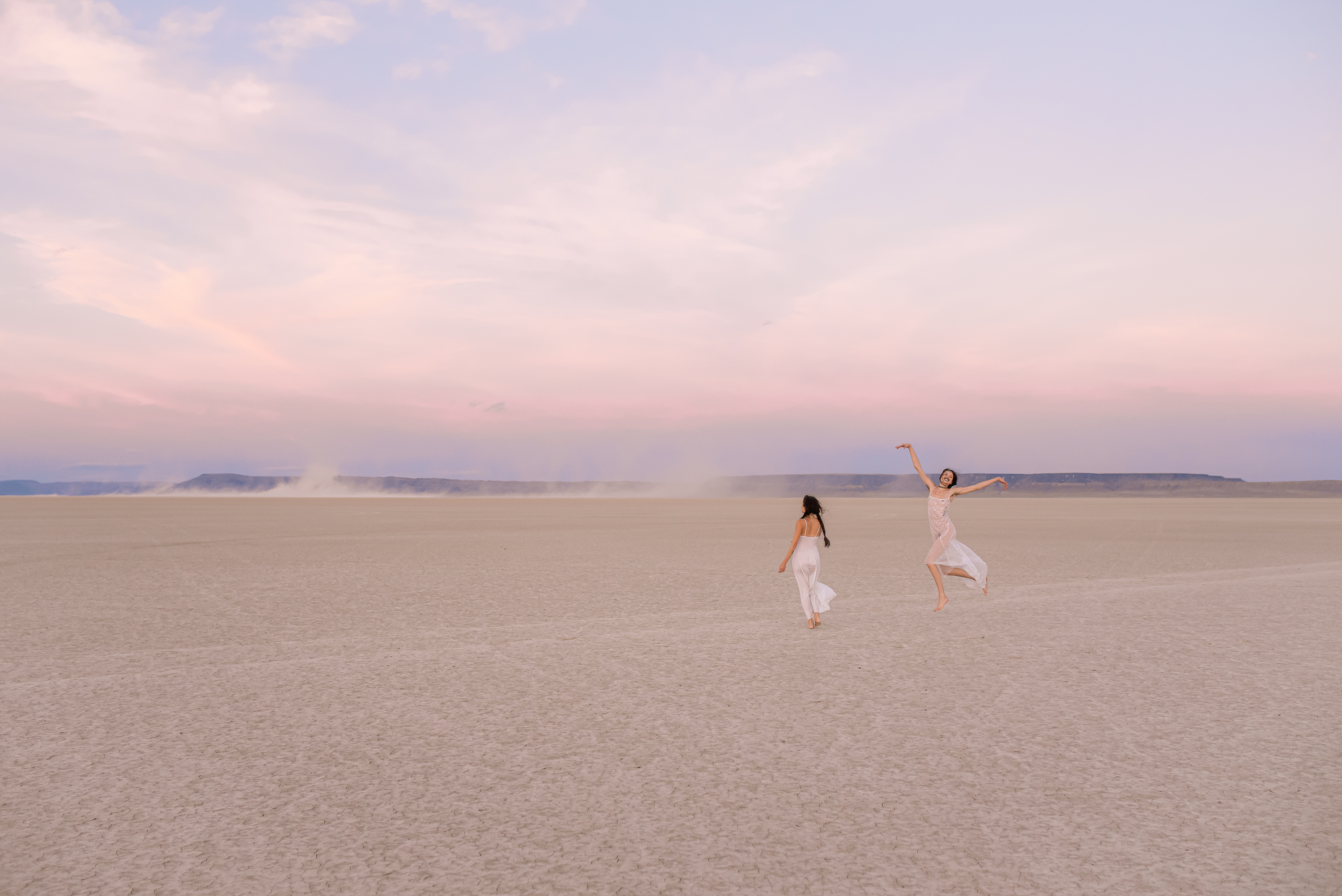 Photograph of two girls jumping in the desert.