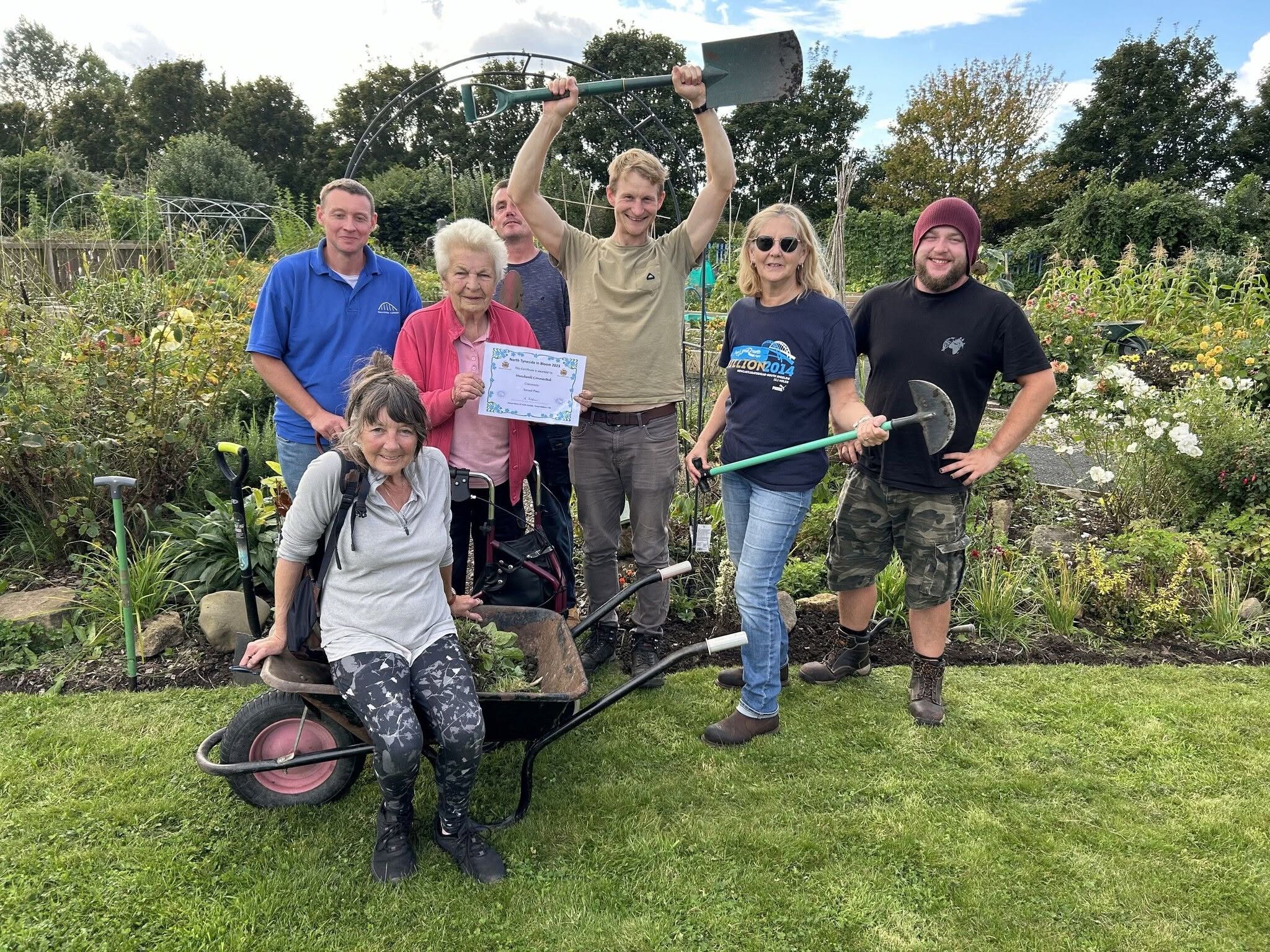Group of staff and volunteers smiling in a community garden