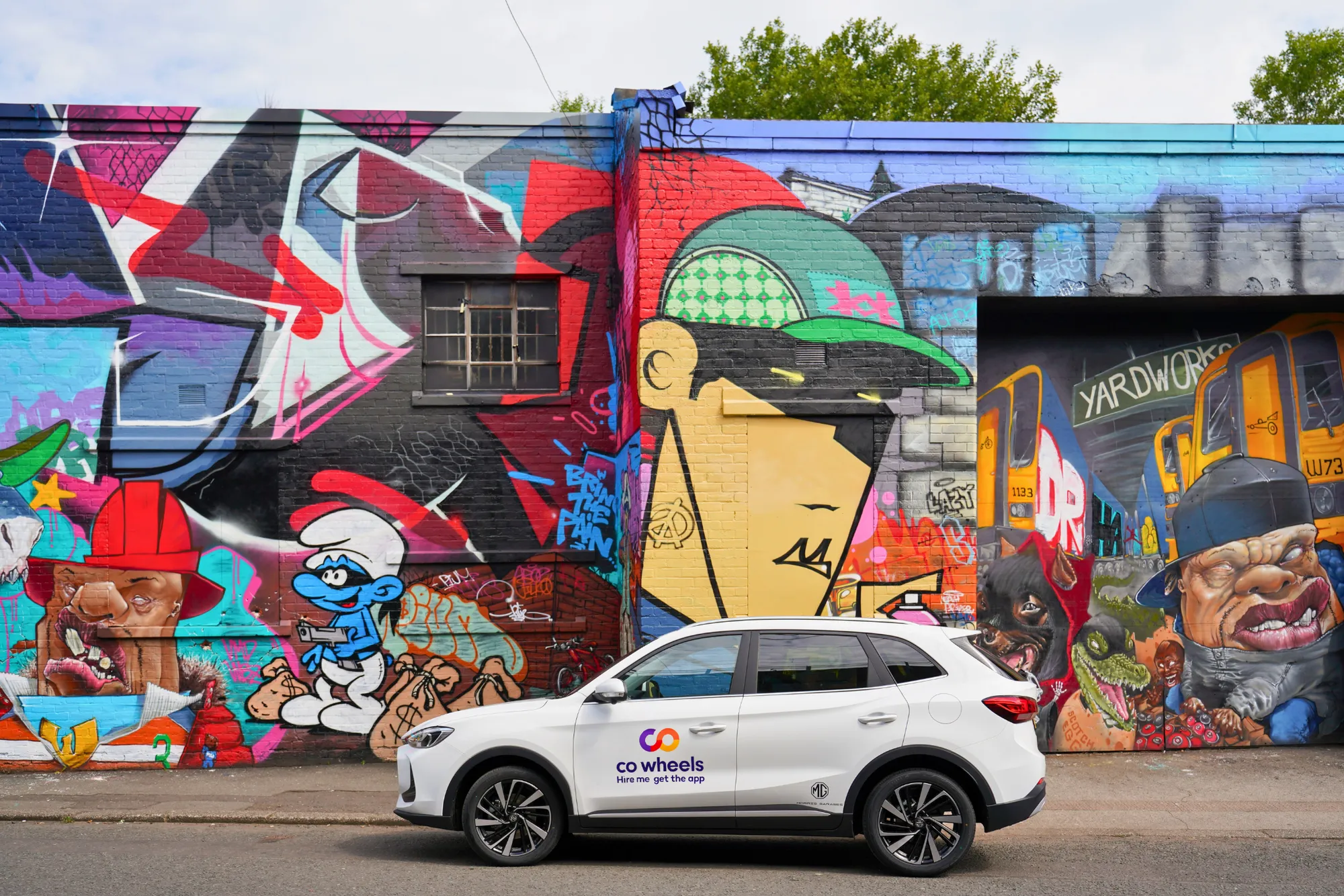 Co Wheels car club vehicle parked in front of graffiti wall