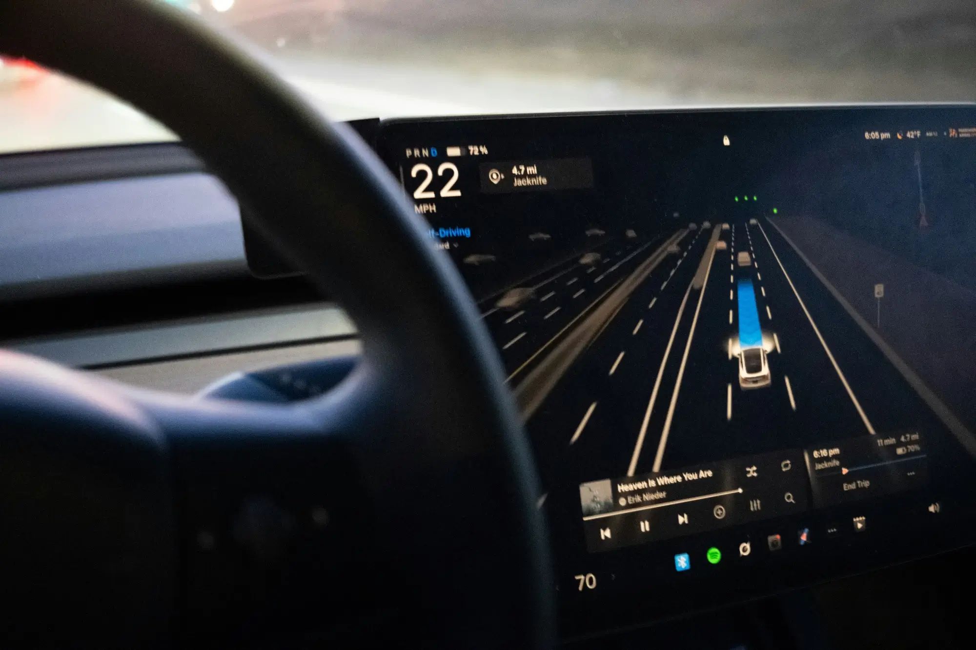 Dashboard screen of a car showing autopilot mode with vehicle, lanes, speed, and media info.