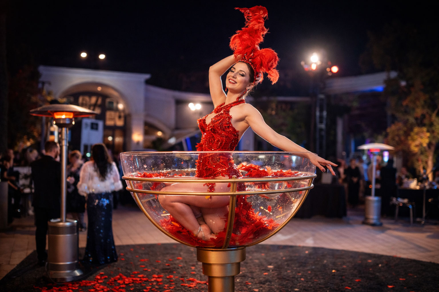 A costumed circus performer balanced inside a martini glass at a corporate gala or themed event.