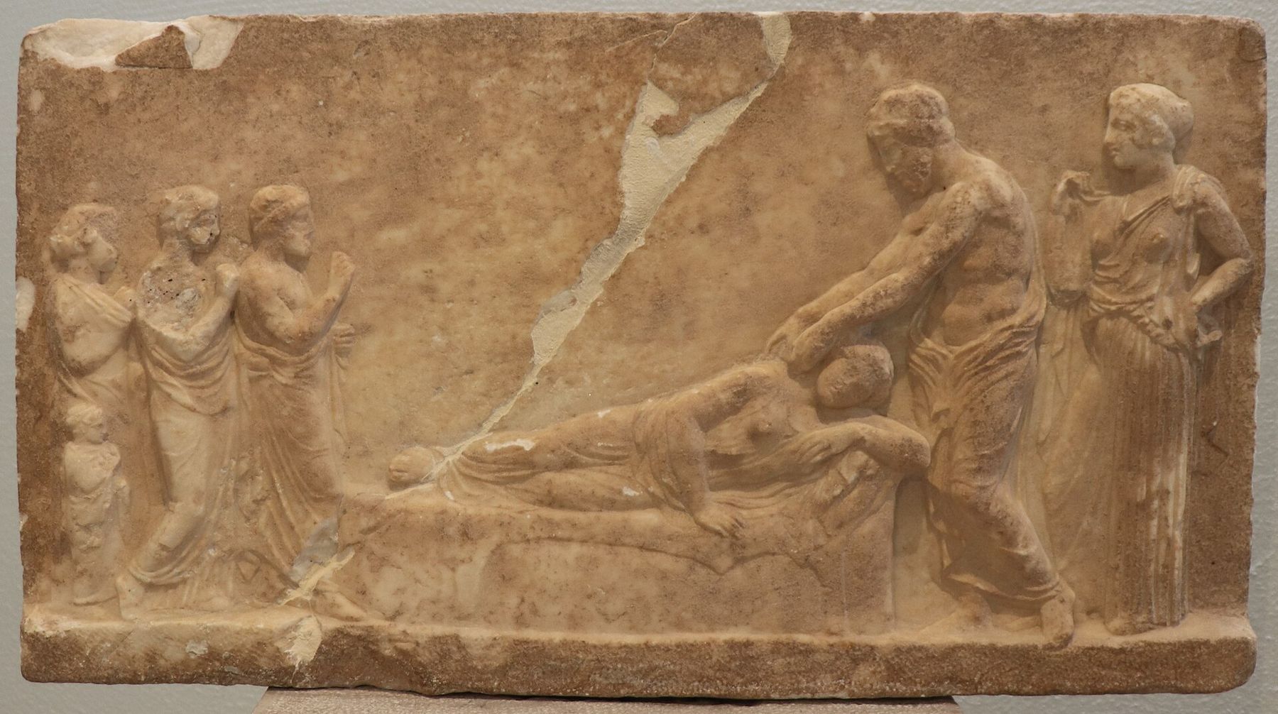 Ancient Greek votive marble relief depicting temple incubation, with a patient asleep and the god attending