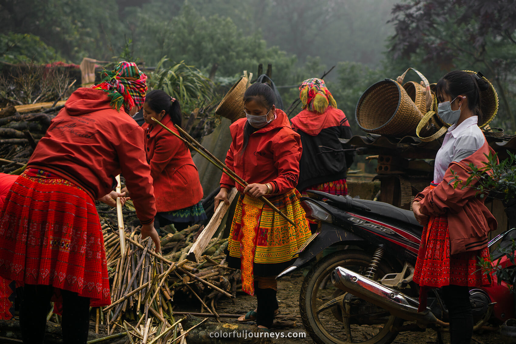 Women wearing colorful dresses cut wood in Vietnam. 