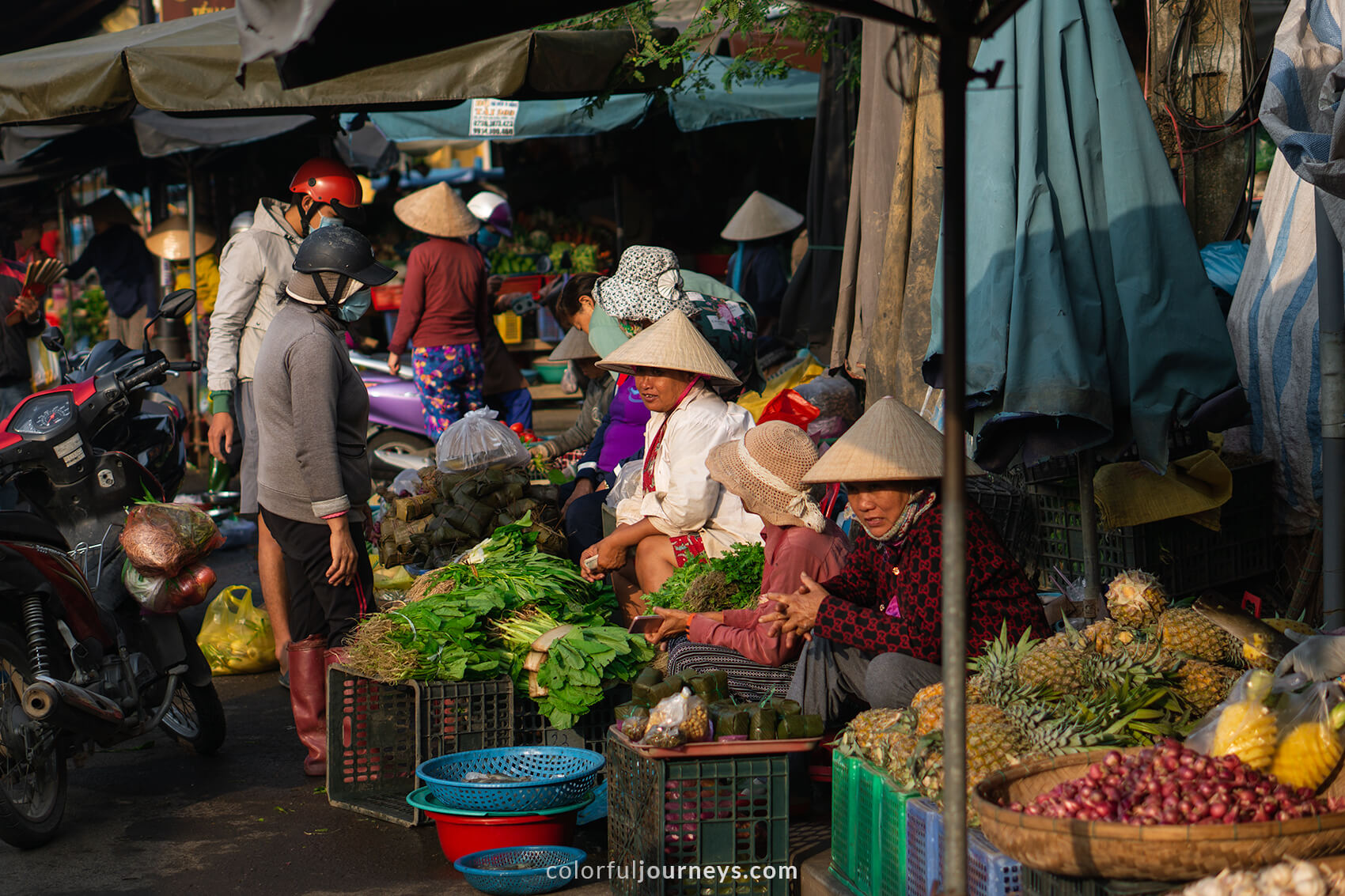 Women wear conical hats at a market in Hoi An, Vietnam.