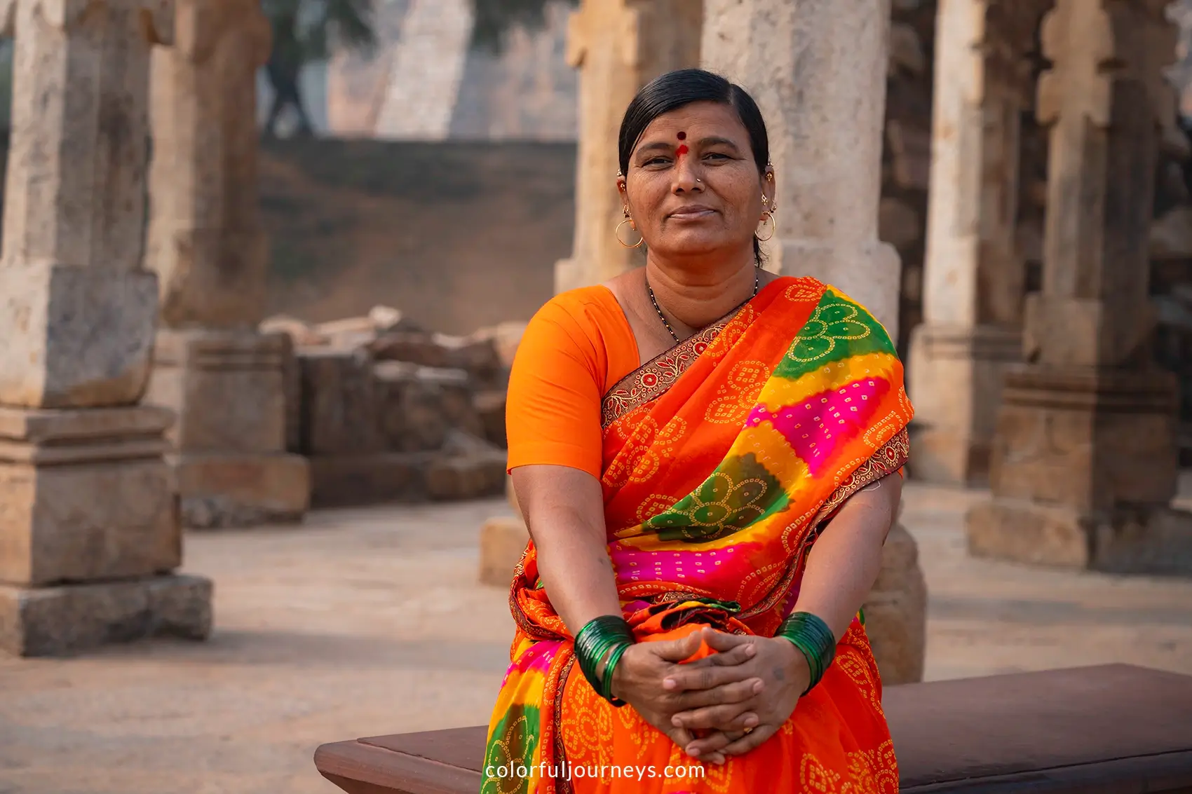 A woman wearing a colorful sari poses for a photo at the Qutub Minar in Delhi, India