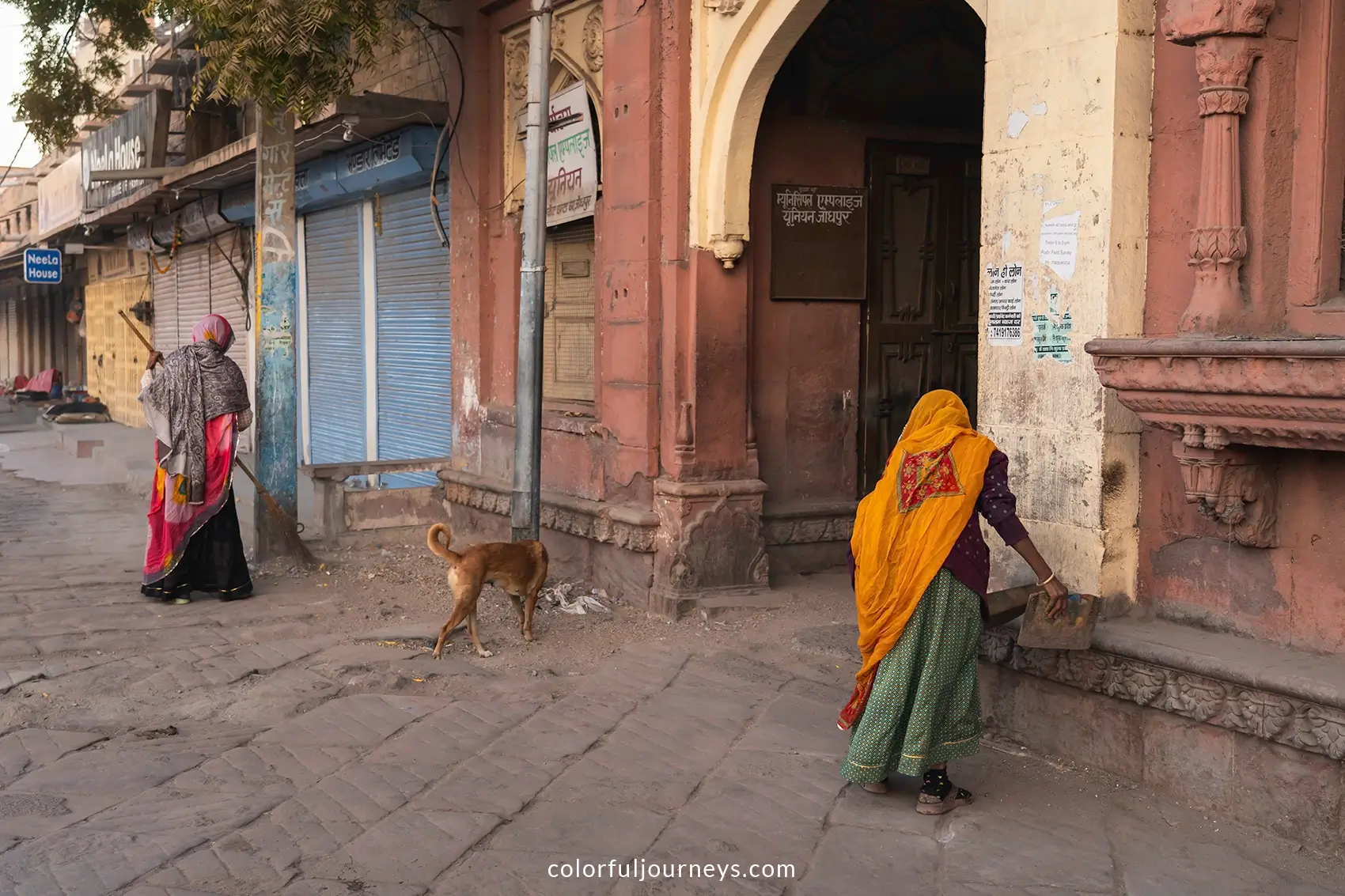 Women wearing sari's sweep the streets of Jodhpur, India
